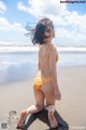 A little girl in a bikini running on the beach.