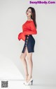 A woman in a red top and blue skirt posing for a picture.