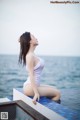 A woman in a white bathing suit sitting on the edge of a swimming pool.