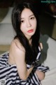 A woman in a striped dress sitting on a bed.