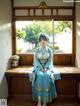 A woman in a blue kimono sitting on a wooden bench.