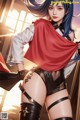 A woman with blue hair wearing a red cape and black stockings.