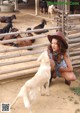 A woman kneeling down next to a dog in a pen.